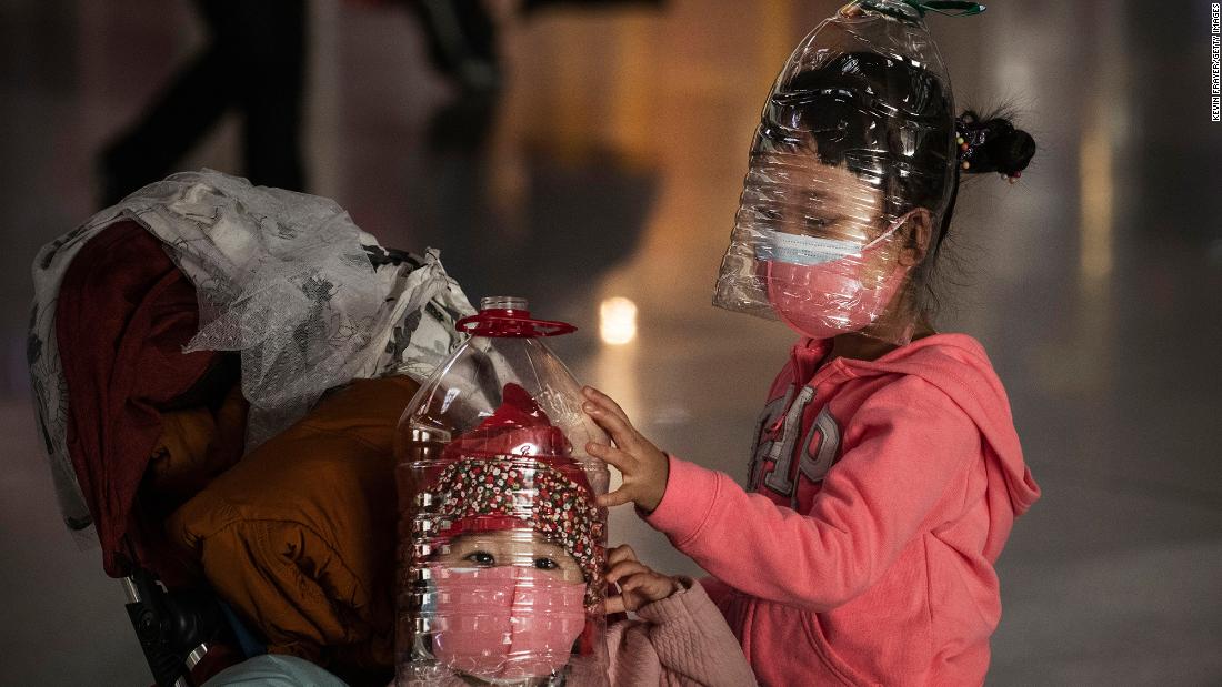 Children wear plastic bottles as makeshift masks while waiting to check in to a flight at the Beijing Capital Airport on January 30.