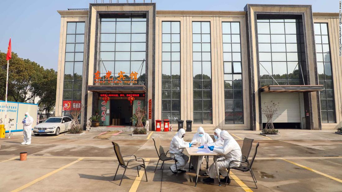 People wearing protective overalls talk outside a Wuhan hotel housing people in isolation on February 3.