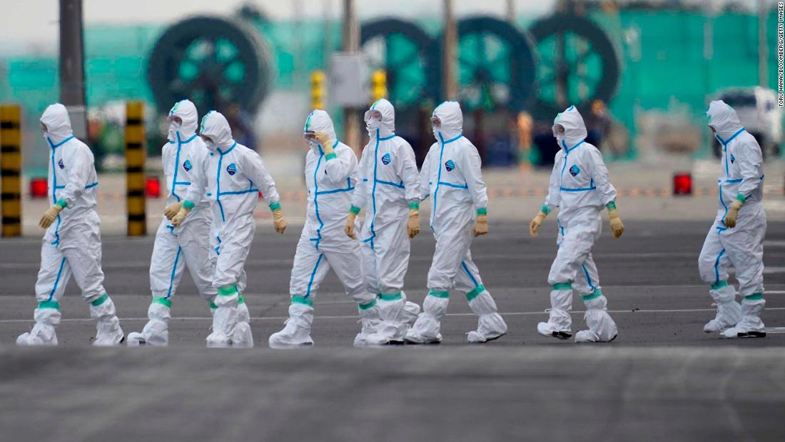 Workers in protective gear walk near the Diamond Princess cruise ship docked in Yokohama on February 7.