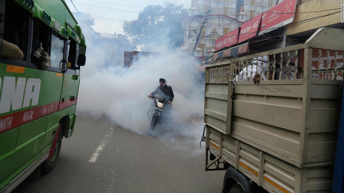 A motorcyclist drives through disinfectant sprayed in Jammu, India, on March 13.
