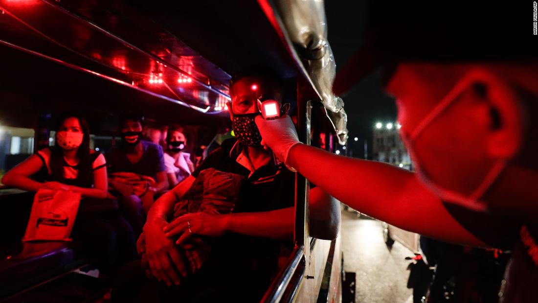 A police officer checks the temperatures of bus passengers at a checkpoint in Manila, Philippines, on March 16.