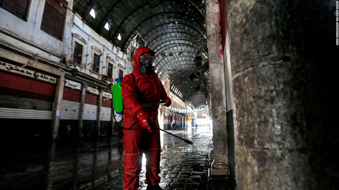 A Syrian Red Crescent member sprays disinfectant along an alley of the historic Hamidiyah market in Damascus, Syria.