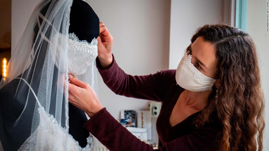 Designer Friederike Jorzig adjusts a mannequin wearing a wedding dress and a face mask at her store in Berlin on March 31.