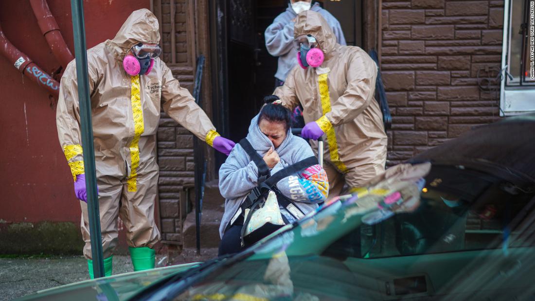 A woman suspected of having coronavirus is helped from her home by emergency medical technicians Robert Sabia, left, and Mike Pareja, in Paterson, New Jersey, on March 24.