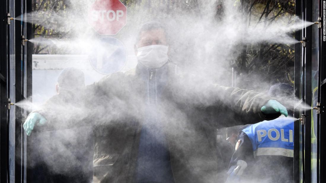 A man is sprayed with disinfectant prior to going to a market in Tirana, Albania, on Monday, April 6.