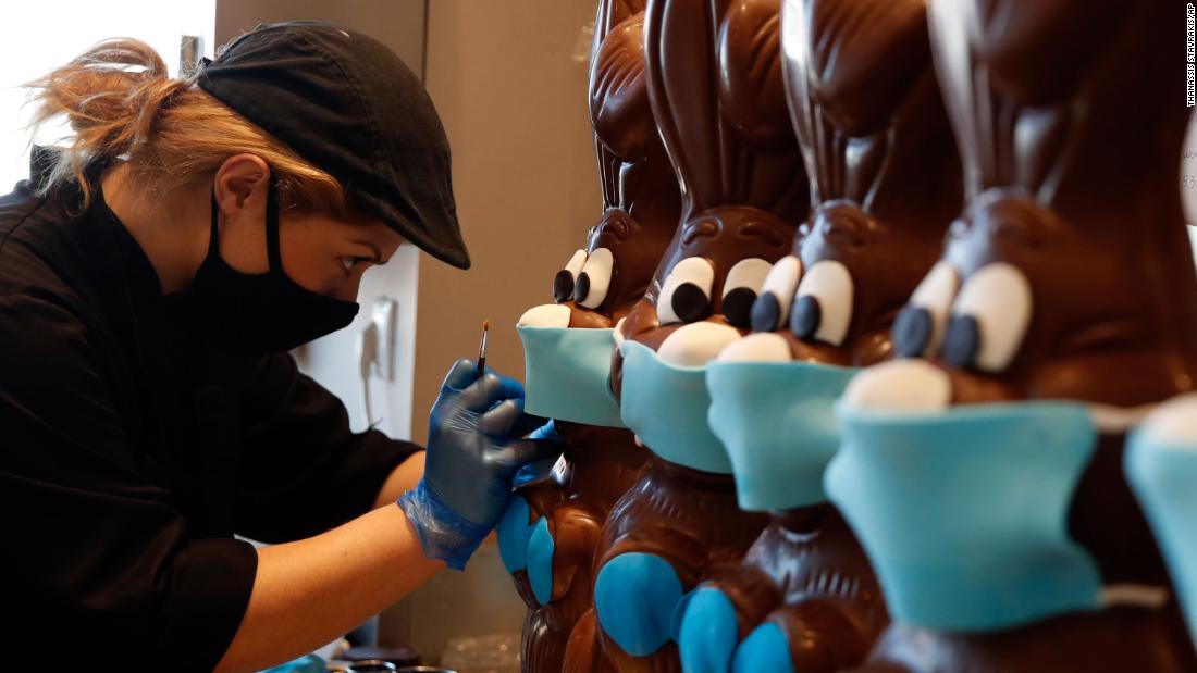 A cake shop employee in Athens, Greece, prepares chocolate Easter bunnies with face masks on April 8.