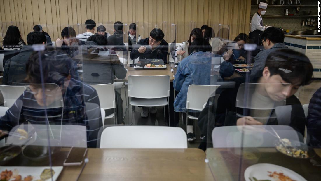 Employees of Hyundai Card, a credit card company, sit behind protective screens as they eat in an office cafeteria in Seoul, South Korea, on April 9.