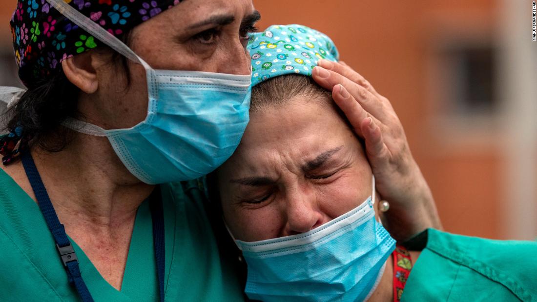 Health workers in Leganes, Spain, cry during a memorial for a co-worker who died because of the coronavirus.