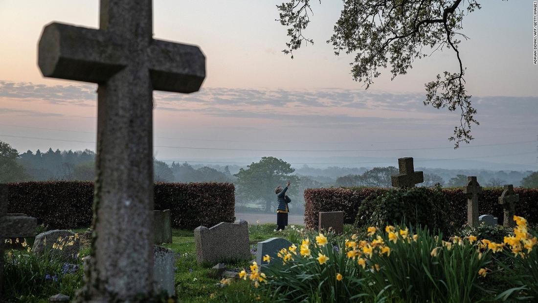 Priest-in-charge Angie Smith uses her phone to broadcast an Easter service from a churchyard in Hartley Wintney, England, on April 12.