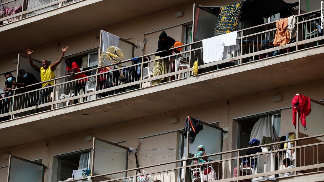 Migrants wave from balconies at a hotel in Kranidi, Greece, on April 21. The shelter, which hosts 470 asylum seekers, was placed in isolation after a pregnant resident tested positive for the novel coronavirus.