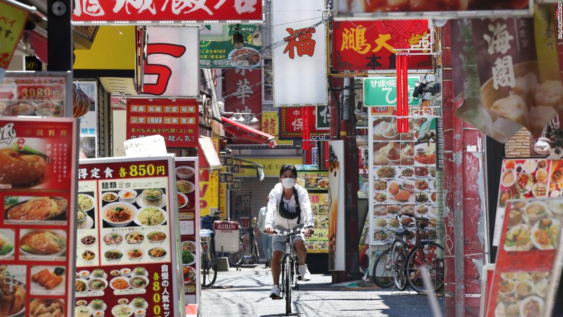 A man wearing a face mask cycles through Chinatown in Yokohama, Japan, on May 8. Prime Minister Shinzo Abe announced that Japan will extend its state of emergency until the end of May.